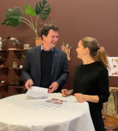 borgmester i Vallensbæk, Henrik Rasmussen, og direktør på ARKEN, Marie Nipper, står ved et rudnt cafébord og smiler til hinanden foran de underskrevne samarbejdsaftaler.