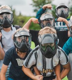 En gruppe unge står med masker på og har positioner som i stærkmands-konkurrencer