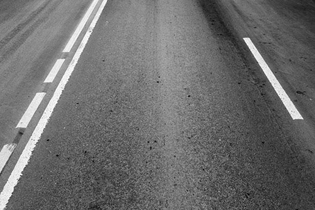 En asfaltvej, hvor der både er fuldt optrukne vejstriber og almindelig stiblede vejstriber.
