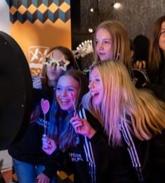 En gruppe unge, storsmilende piger står foran en selfieudløser og laver et gruppefoto.