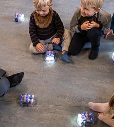 Børn leger med robotter på gulvet.