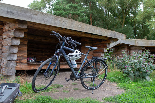 En cykel står foran et klassisk shelter af træbjælker
